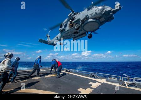 PHILIPPINISCHES MEER (Jan 19, 2022) an Bord des Arleigh Burke-Klasse-Lenkrakenzerstörers USS Spruance (DDG 111) führen Seeleute einen Hubschrauber während des Fluges mit einem MH-60R Seahawk-Hubschrauber an, der an die „Raptors“ des Helicopter Maritime Strike Squadron (HSM) 71 befestigt ist. Als Teil der US-Pazifikflotte führt Spruance Schulungen durch, um eine freie und offene Region im Indo-Pazifik-Raum zu erhalten und zu schützen. (USA Navy Foto von Mass Communication Specialist 3rd Class Taylor Crenshaw) Stockfoto