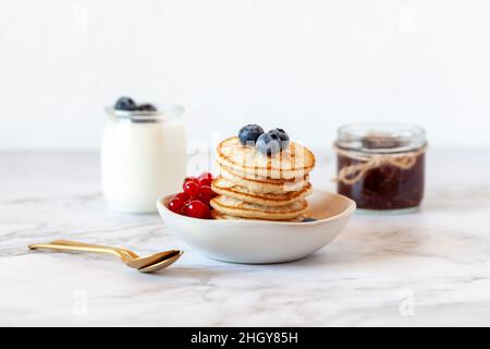 Stapel von glutenfreien Pfannkuchen mit Heidelbeeren und roten Johannisbeeren, selektiver Fokus dekoriert Stockfoto