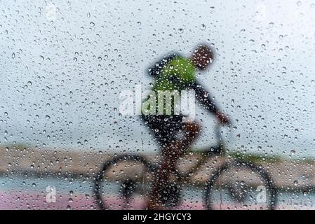 Salvador, Bahia, Brasilien - 15. November 2021: Eine Person, die im Regen mit dem Fahrrad fährt. Salvador, Bahia, Brasilien. Stockfoto