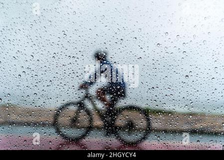 Salvador, Bahia, Brasilien - 15. November 2021: Eine Person, die im Regen mit dem Fahrrad fährt. Salvador, Bahia, Brasilien. Stockfoto