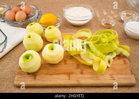 Apfelkuchen mit Biskuit-Basis Rezept. Geschälte grüne Äpfel aus der Nähe auf einem Holzbrett auf rustikalem Hintergrund Stockfoto