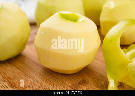 Geschälte grüne Äpfel aus der Nähe auf einem Holzbrett auf dem Küchentisch, Kochvorgang, Apfelkuchen-Rezept Stockfoto