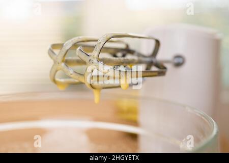 Mischerblätter aus der Nähe. Eier mit Zucker mit einem elektrischen Mixer mischen. Apfelkuchen mit Biskuit Basis Rezept, Schritt für Schritt Backprozess Stockfoto