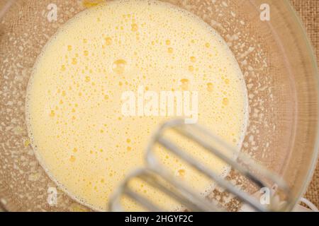 Mischen Sie Eier und Zucker in einer Glasschüssel, flach legen. Eier mit Zucker mit einem elektrischen Mixer mischen. Apfelkuchen mit Biskuit-Basis Rezept, Schritt für Schritt Stockfoto