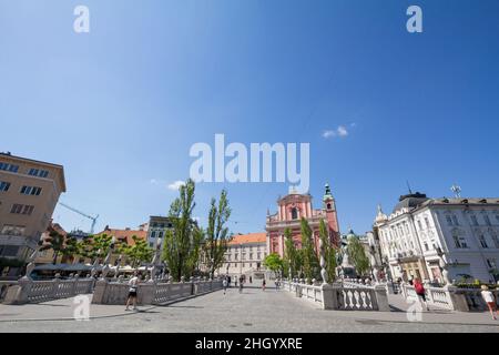 Bild von Menschen, die während eines sonnigen Sommers nach Ljubljana auf der Tromostovje-Brücke (Dreifachbrücke) zwischen dem Presernov-Platz und dem älteren Teil von Ljubljana wandern Stockfoto