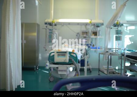 Bewusstloser Patient auf der Intensivstation unter der Überwachung der Uhr, unfokussierter Hintergrund. Stockfoto