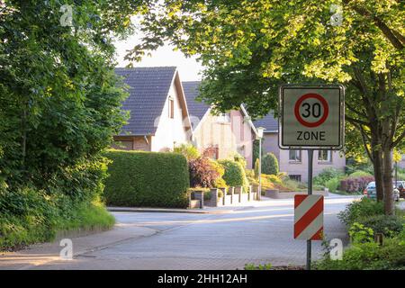 Ansicht des Verkehrsschildes in Itzehoe, Deutschland mit Haus, Bäumen, Laub, Straße und hellem Sonnenlicht im Hintergrund. Keine Personen. Stockfoto