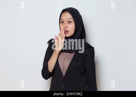 Junge asiatische muslimische Geschäftsfrau schockiert, den Mund aus Versehen mit Händen zu bedecken. Geheimes Konzept. Stockfoto