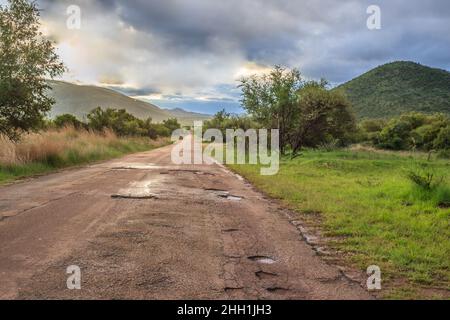 Eine feuchte Landschaft Blick auf Berge, braun und grün Savanne Grasland bedeckt mit Wassertropfen und regen Pfützen nach einem Regensturm, Pilanesburg Stockfoto