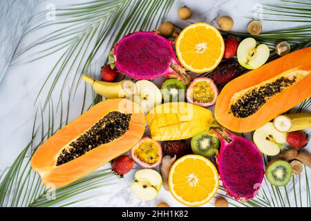 Gruppe exotischer tropischer Früchte. Papaya, Mango, Drachenfrucht, Passionsfrucht, Kiwi, Erdbeere, apfel, Banane, Orange, Langaan, grüne Blätter auf weißer BA Stockfoto