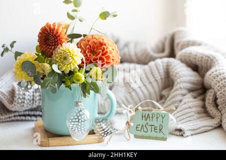 Osterkomposition mit einem Blumenstrauß und einem gestrickten Element. Stockfoto