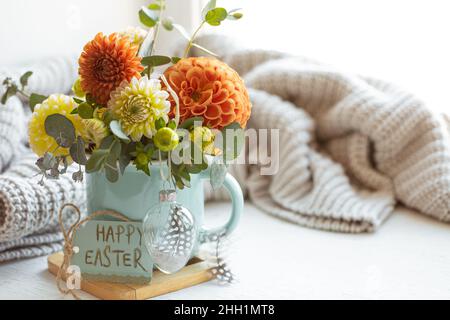 Osterkomposition mit einem Blumenstrauß und einem gestrickten Element. Stockfoto