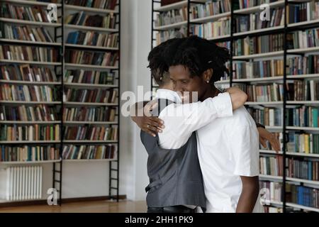 Fröhliche, multiethnische Studenten grüßen in der Bibliothek Stockfoto