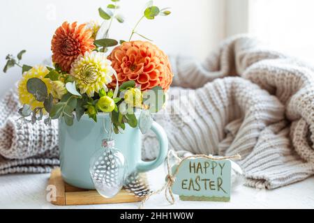 Osterkomposition mit einem Blumenstrauß und einem gestrickten Element. Stockfoto