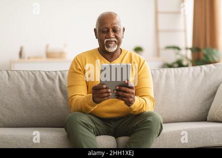 Senior African American Männlich Mit Digitalen Tablet Lesung Online Indoor Stockfoto
