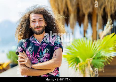 Gemischter Rennmensch mit lockigen langen Haaren im Freien an einem sonnigen Tag Stockfoto