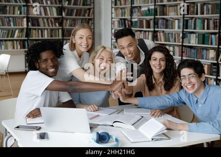 Gemischtes Rennteam aus glücklichen Studenten, die der Gruppe fünf Punkte geben Stockfoto