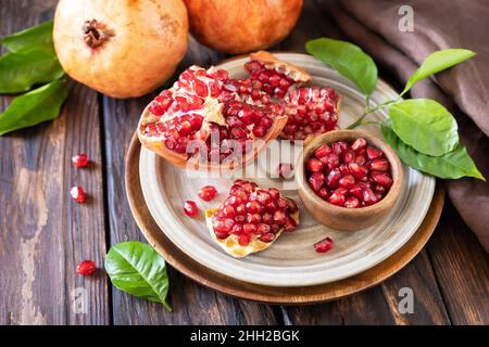 Reife saftige Granatapfelfrüchte in einer Holzschüssel auf einem rustikalen Tisch. Ernährung und gesunde Ernährung. Stockfoto