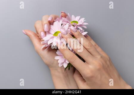 Weibliche Hände mit rosa glitzernder Maniküre auf grauem Hintergrund Stockfoto