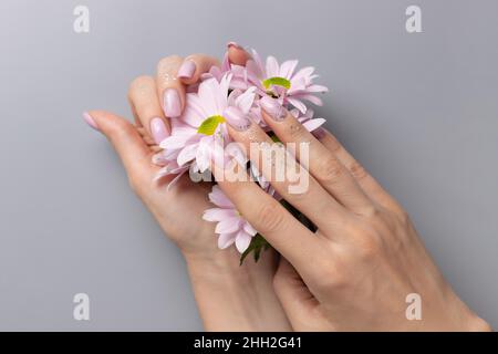 Weibliche Hände mit rosa glitzernder Maniküre auf grauem Hintergrund Stockfoto