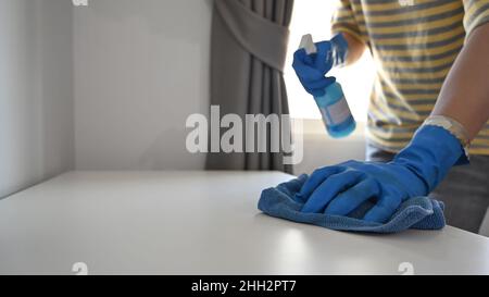 Beschnittenes Bild Mann trägt Gummihandschuhe, Reinigungstisch mit Lappen und Sprühreiniger. Stockfoto