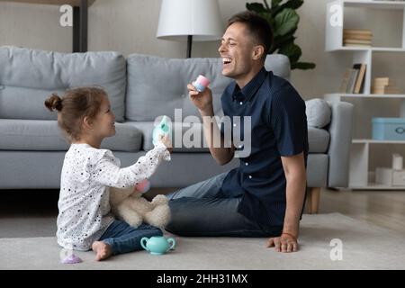 Liebenswert kleines Kind Mädchen spielen mit lachenden Vater. Stockfoto