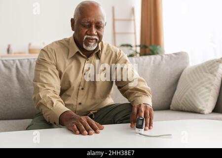 Senior Black Man Misst Die Sättigungsstufe Mit Dem Pulsoximeter Im Innen-Bereich Stockfoto