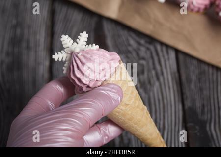 Rosafarbenes Sumpfgebiet in Waffelkegel. Zechyr in Waffelkonen. Dekoriert mit dekorativen Streuseln und mastistischen Schneeflocken. Stockfoto