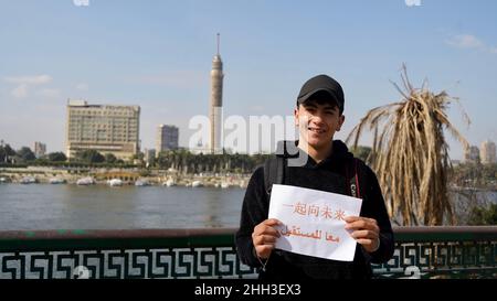 Peking, Ägypten. 18th Januar 2022. Salah, eine Fotografin, posiert mit einem Papierdruck "Together for a Shared Future", dem offiziellen Motto für Peking 2022, am 18. Januar 2022 in Kairo, Ägypten. Weniger als zwei Wochen vor dem Beginn der Olympischen Winterspiele 2022 in Peking bringen Menschen auf der ganzen Welt ihre Freude über die sportliche Extravaganz zum Ausdruck. Quelle: Wang Dongzhen/Xinhua/Alamy Live News Stockfoto