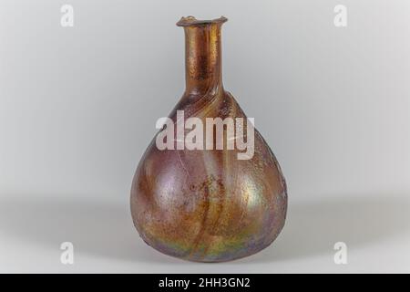 Parfümflasche aus Glas Anfang bis Mitte des 1st. Jahrhunderts n. Chr. Roman Durchscheinend streifendes, blassviolettes Purpur.Everted Rand mit abgeschrägter Oberkante; zylindrischer Hals, mit leichter horizontaler Vertiefung um den Boden; konischer Körper, der sich zu leicht konkavem Boden einbiegt.am Oberkörper eine breite, horizontal geschnittene Nut.intakt, außer großer Chip im Rand mit verwitterten Kanten; Blasen und Blasen einstechen; stumpfes, tiefes Lochfraß und schillerndes Äußeres, Flecken schillernder Verwitterung im Inneren. Parfümflasche aus Glas. Römisch. Früh–Mitte des 1st. Jahrhunderts n. Chr. Glas; geblasen und geschnitten. Frühkaiserlich, Julio-Claudian. Gl Stockfoto