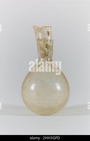 Glaskolben 3rd. Jahrhundert n. Chr. römisch farblos.einfacher, geschliffender Rand; trichterförmiger Hals, mit horizontaler Einrückung um den Boden; piriformer Körper; kleiner, leicht konkaver Boden.am Hals und Körper Bänder mit horizontalen Schnittzeilen, einzeln, paarweise und in Gruppen angeordnet; Drei Bänder am Hals und sechs am Körper.Körper komplett, aber gebrochen am Hals, mit einem Teil des Randes und des Halses fehlt, und einige innere Risse im Körper; Nadelstich und längliche Blasen, und Blasen Streifen; Flecken von Bodenverkrustungen, milchige Verwitterung, und irisierende auf dem Inneren.. Glaskolben. Roman. 3rd Jahrhundert n. Chr.. Glas; geblasen und geschnitten. Späte Impe Stockfoto