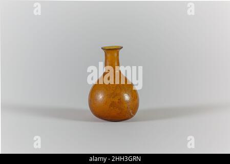 Parfümflasche aus Glas Mitte des 1st. Jahrhunderts n. Chr., römisch, durchscheinend, honiggelb, mit feuergerundeter Lippe; zylindrischer Hals, mit horizontaler, eingedornter Einkerbung um den Boden; Knollenkörper; leicht konkaver Boden. Intakt; einige Nadelstrüpp-Blasen; stumpfend, Etwas Lochfraß, und leichte Verwitterung auf der Außenseite, Bodenverkrustungen auf der Unterseite und schillernde Verwitterung auf Seite und Hals des Inneren.. Parfümflasche aus Glas. Römisch. Mitte des 1st. Jahrhunderts A.D. Glas; geblasen. Frühkaiserlich. Glas Stockfoto
