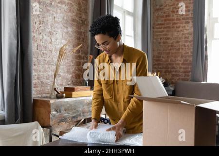 Junge afroamerikanische Logistikanstellerin Frau, die Waren verpackt Stockfoto