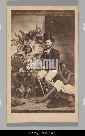 [Studio Portrait: Man Wearing Top hat Seated with 2 Indigenous People] 1860s–70s Unbekannt die Carte de Visite, ein Format bestehend aus einem ca. 2 x 4 Zoll großen Foto, das auf Karton montiert ist, war vielleicht die allgegenwärtige Fotografie des 19. Jahrhunderts. Der französische Porträtfotograf André-Adolphe-Eugène Disdéri patentierte das Carte erstmals 1854. Seine Innovation, nicht nur ein, sondern acht fotografische Bilder auf demselben Glasplatten-Negativ zu belichten, ermöglichte es, Kartons kostengünstig zu erstellen und im Massenmaßstab zu reproduzieren. Ende 1850s und in der zweiten Hälfte des Jahrhunderts Stockfoto