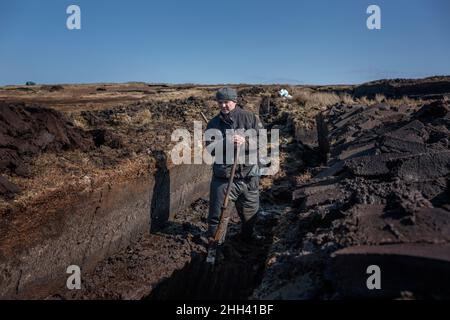 Ein irischer Rasenmäher, der mit einem Sleán Rasenflächen schneidet, die traditionelle Art des Rasenmähens, wie es seit Ewigkeiten gemacht wird. Stockfoto