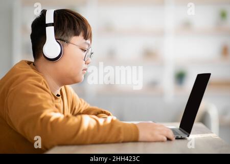 Seitenansicht eines asiatischen Teenagers mit Laptop und leerem Bildschirm Stockfoto