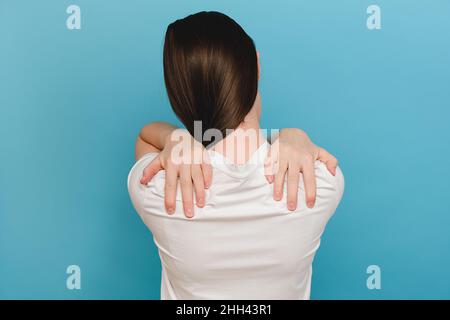 Zervikale Osteochondrose. Nahaufnahme der müden jungen Brünette Frau im Alter von 20s Jahren, die unter Nackenschmerzen litt, ihren entzündeten Körper berührte und posierte Stockfoto