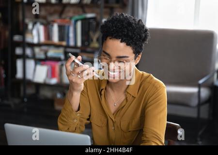 Glückliche afroamerikanische Unternehmerin, die eine Audiobotschaft aufzeichnet Stockfoto