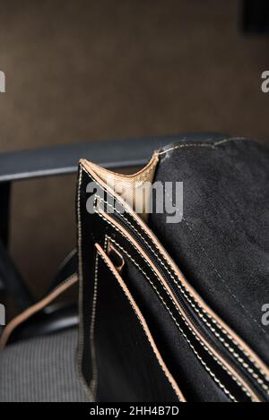 Offene Aktentasche aus schwarzem Leder mit antikem und Retro-Look für einen Mann auf einem Bürostuhl. Foto in einem Konferenzsaal aufgenommen Stockfoto