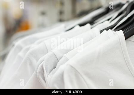 Einige benutzten Kleidung, die auf einem Flohmarkt auf einem Regal hing. Hintergrund des Kleides. Selektiver Fokus. Stockfoto