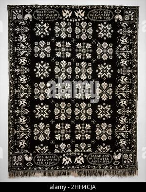 Coverlet 1834 David Daniel Haring American Dieses dunkelblaue Doppel-Tuch aus Wolle und ungefärbter Baumwolle ist in zwei Platten gewebt und in der Mitte gezähmt. Blumen- und Sternmotive, die in Harings Arbeiten typisch sind, schmücken das zentrale Feld. Die linke und rechte Grenze zeigen Bilder von Adlern mit ausgebreiteten Flügeln, die sich mit Vasen von Blumen und Vogelpaaren in Bäumen abwechseln. Von links nach rechts entlang jeder Tafel des oberen und unteren Rändern steht ein Hahn auf einem Ei, die Inschrift Kartusche und ein Adler. Das Haring-Markenzeichen einer Rose mit vier Blättern auf ihrem Stamm erscheint in jeder Ecke b Stockfoto