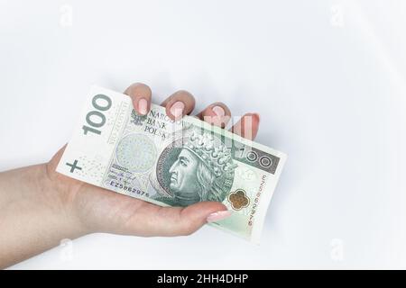 Hundert Zloty - polnische Banknote. Die polnische Währung hielt sich vor weißem Hintergrund in der Hand Stockfoto