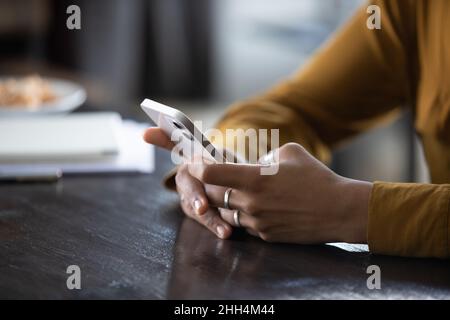 Hände einer jungen dunkelhäutigen Frau, die die App am Telefon nutzt Stockfoto