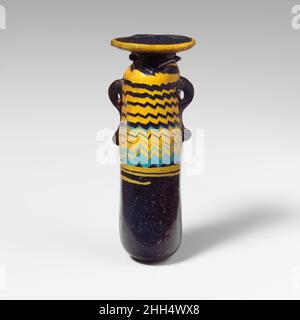 Glas-Alabastron (Parfümflasche) Ende 6th–5th Jahrhundert v. Chr. Griechisch, östliches Mittelmeer Durchscheinendes Blau, gestreift mit rötlich-violettem Purpur, mit Griffen in gleicher Farbe; Trails in opak-gelbem und opak-türkisblauem Blau; breite, unebene horizontale Randscheibe, mit leicht erhöhtem Rand um den Mund, der sich über den Hals und die Traildekoration erstreckt; Kurzer zylindrischer Hals; ungleichmäßige abgerundete Schulter; gerader zylindrischer Körper; konvexer Boden; Zwei vertikale Ringgriffe mit geklopften Schwänzen, über der Traildekoration angebracht.Gelber Trail am Rand der Randscheibe befestigt; ein zweiter gelber Trail am Hals angebracht und Stockfoto