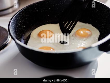 Person, die in der Bratpfanne zum Frühstück Spiegeleier zubereitet. Stockfoto