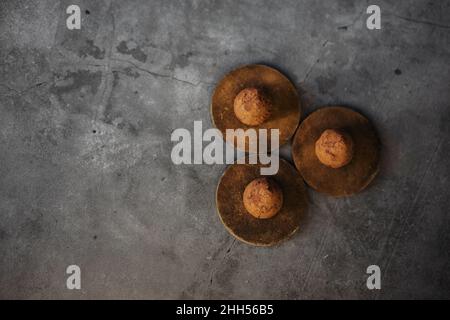 Schokoladentrüffel auf dunklem Hintergrund, Tischansicht von oben. Hausgemachte dunkle Schokoladen-Butter-Trüffel mit Kakaopulver und Kaffee Stockfoto