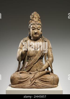 Bodhisattva Avalokiteshvara (Guanyin) Ende des 10th.–Anfang des 11th. Jahrhunderts China Es ist selten, eine Skulptur von Avalokiteshvara zu finden, die wie in der Meditation sitzend mit seinen Beinen gefaltet ist. Meistens wird er stehend oder sitzend mit einem gebeugten Bein und dem anderen hängenden Bein gezeigt – eine Pose, die als „königliche Leichtigkeit“ bekannt ist. Eine Ausnahme ist, wenn Avalokiteshvara in Szenen des Reinen Landes des Buddha Amitabha erscheint. Es ist möglich, dass diese Skulptur Teil einer solchen Komposition war. Bodhisattva Avalokiteshvara (Guanyin). China. Ende des 10th.–Anfang des 11th. Jahrhunderts. Holz (Fuchshandschuh) mit Pigmenten, Vergoldung, Quarz und Karneol; Einzelholz Stockfoto