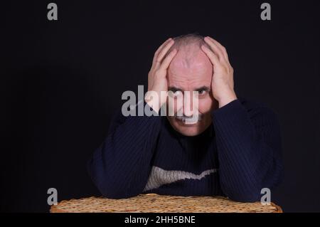 Schönes Porträt von nachdenklichen kaukasischen reifen Mann mit Armen umgefalteten Kopf in Low-Key Stockfoto
