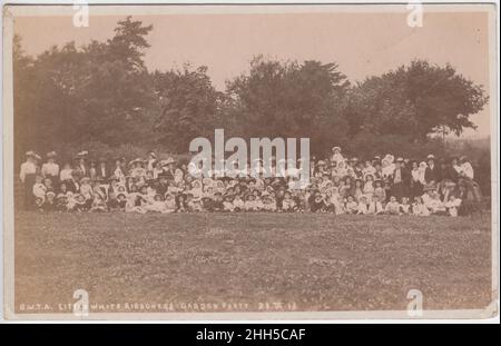 British Women's Temperance Association (BWTA) Little White Ribboners Gartenparty, Ryde, Isle of Wight, 1913. Große Gruppe von Kindern, die draußen sitzen, mit Frauen (in Hüten), die hinter ihnen stehen Stockfoto