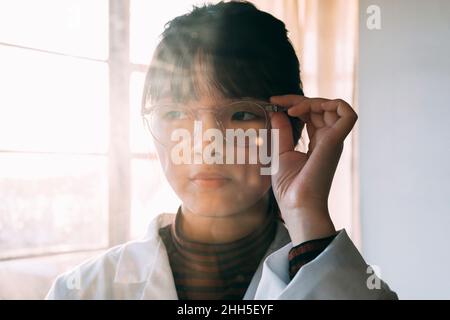 Junge Wissenschaftlerin, die eine Brille trägt und im Labor wegschaut Stockfoto